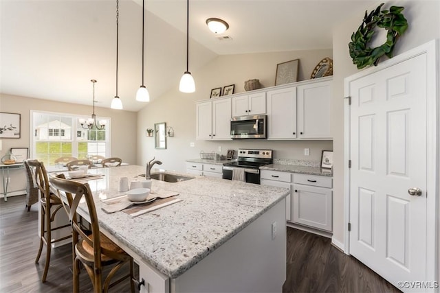 kitchen with white cabinetry, stainless steel appliances, hanging light fixtures, and an island with sink