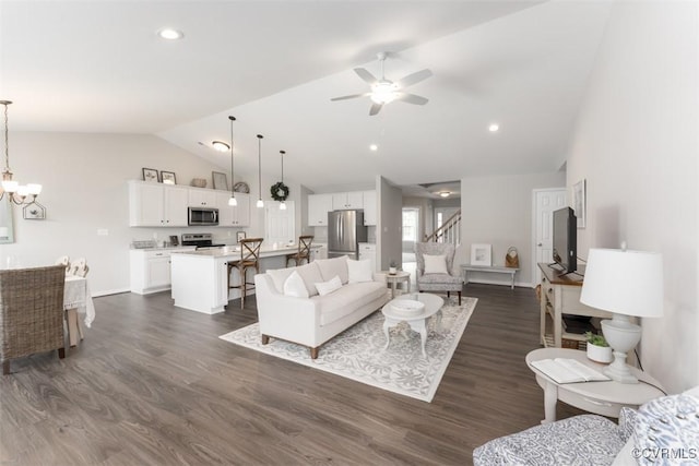 living room featuring ceiling fan with notable chandelier, dark hardwood / wood-style floors, and vaulted ceiling