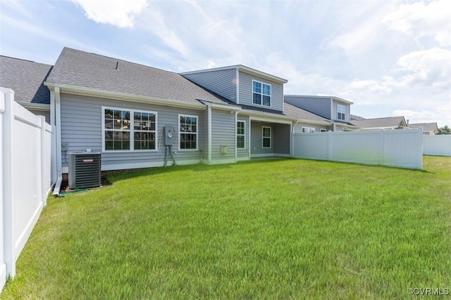 back of house with central AC unit and a lawn