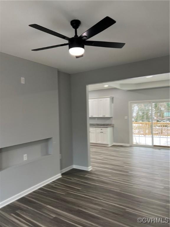 unfurnished living room featuring ceiling fan and dark wood-type flooring