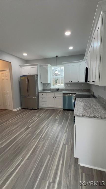 kitchen with white cabinets, hanging light fixtures, appliances with stainless steel finishes, and hardwood / wood-style floors