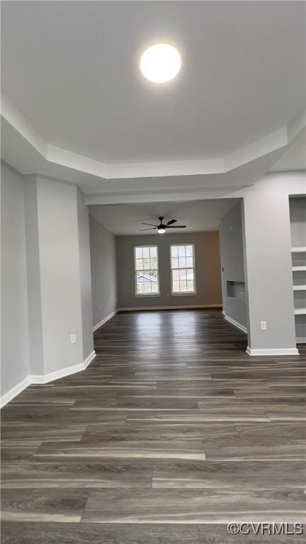 unfurnished room with a tray ceiling, ceiling fan, and dark hardwood / wood-style floors