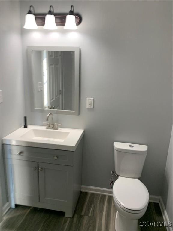 bathroom with hardwood / wood-style floors, vanity, and toilet