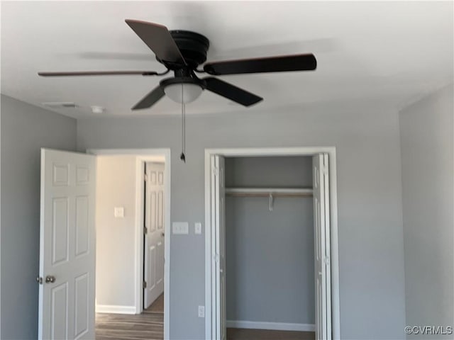 unfurnished bedroom featuring ceiling fan, a closet, and wood-type flooring