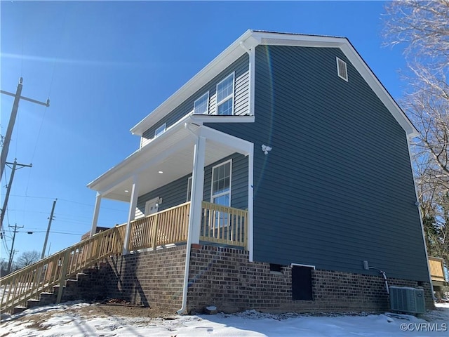 view of snow covered exterior with a porch and central air condition unit