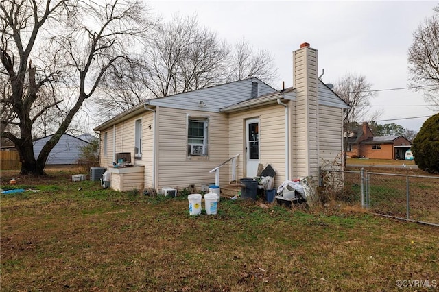 rear view of property featuring central AC unit and a lawn