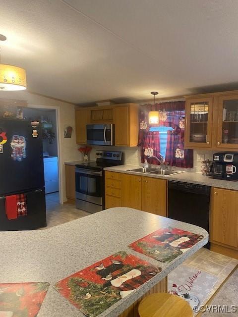 kitchen with sink, black appliances, washer / dryer, vaulted ceiling, and decorative light fixtures