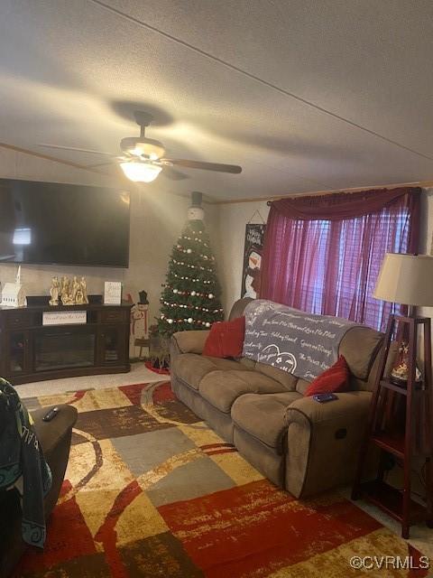 living room with ceiling fan, a fireplace, and a textured ceiling