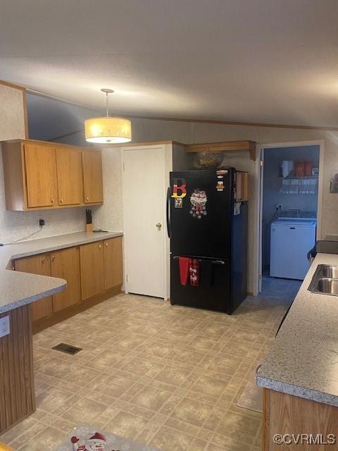 kitchen with black refrigerator, washer / clothes dryer, sink, and hanging light fixtures