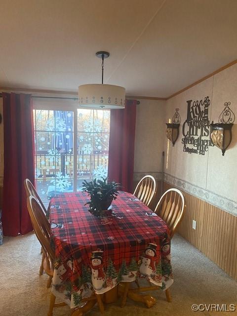 dining room featuring wooden walls, ornamental molding, and carpet