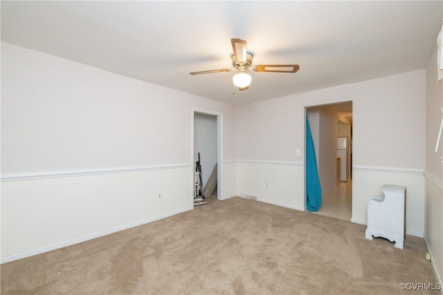 empty room featuring ceiling fan and light carpet