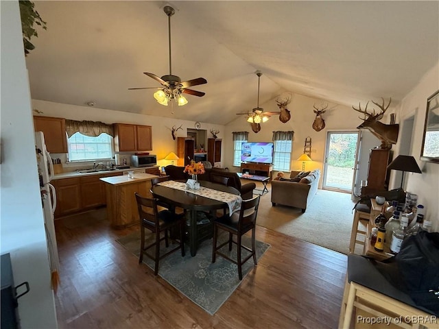 dining space with vaulted ceiling, ceiling fan, dark wood-type flooring, and sink