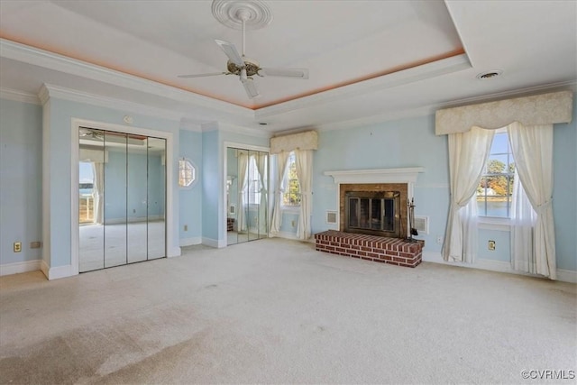 unfurnished living room with light carpet, a raised ceiling, ceiling fan, ornamental molding, and a fireplace