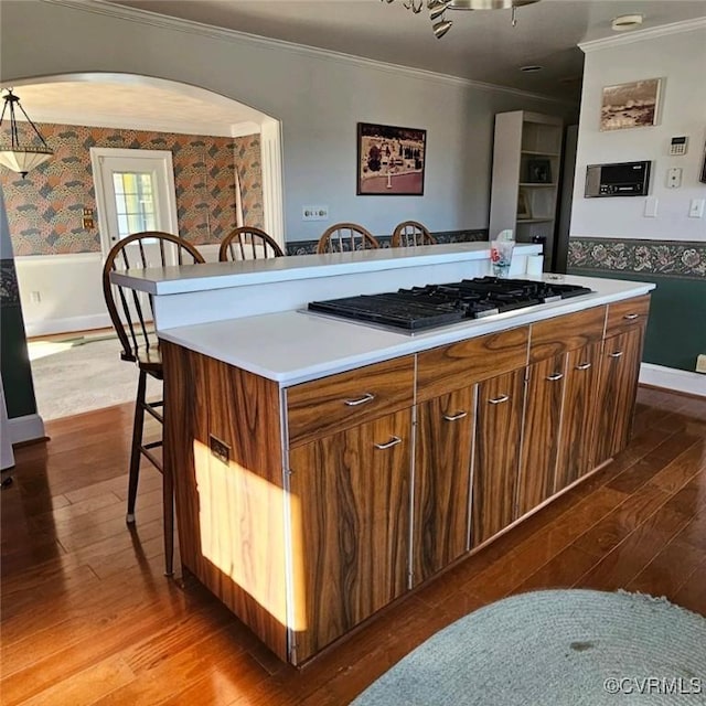 kitchen featuring a kitchen bar, gas stovetop, a kitchen island, and crown molding