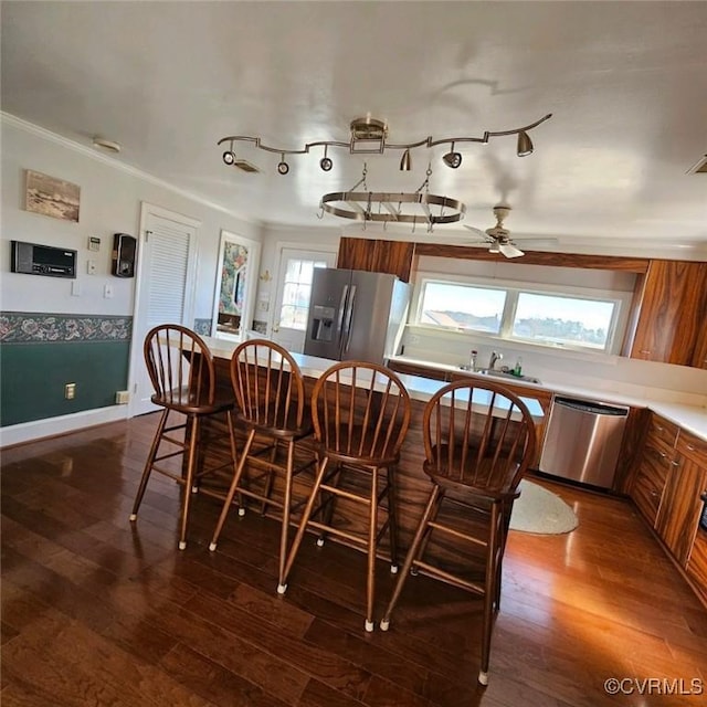 kitchen with appliances with stainless steel finishes, ceiling fan, crown molding, sink, and wood-type flooring