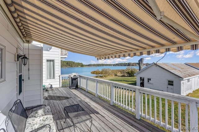 wooden terrace featuring a grill, a water view, and an outdoor structure