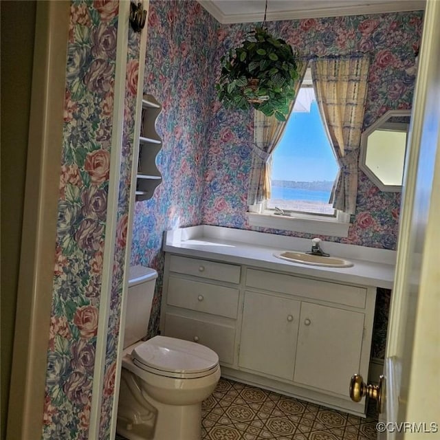 bathroom featuring tile patterned flooring, crown molding, toilet, a water view, and vanity