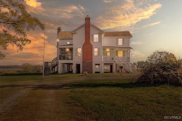 back house at dusk with covered porch and a lawn