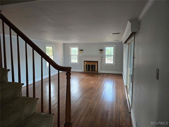 unfurnished living room with hardwood / wood-style flooring and crown molding