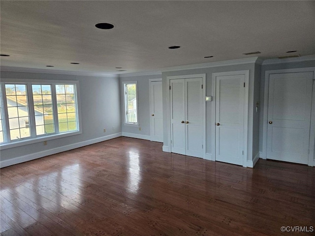 unfurnished bedroom with multiple closets, hardwood / wood-style floors, and ornamental molding