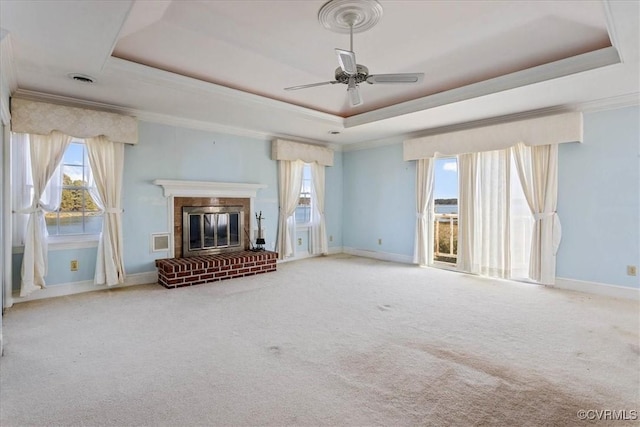 unfurnished living room with a raised ceiling, ceiling fan, carpet floors, and a brick fireplace