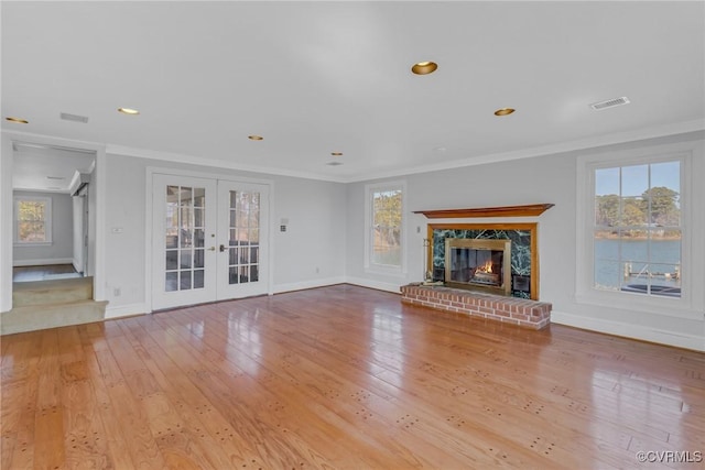 unfurnished living room with visible vents, french doors, crown molding, and hardwood / wood-style flooring