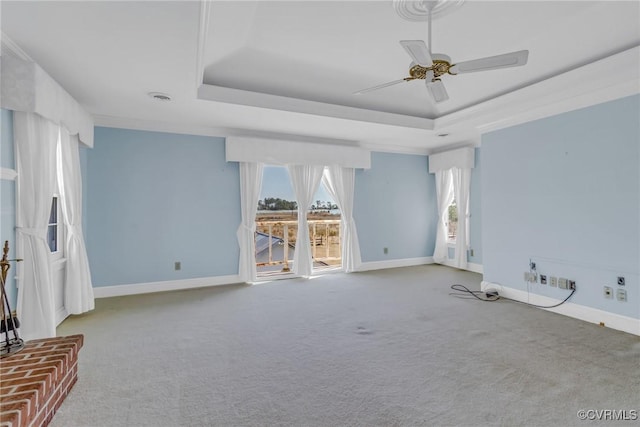 unfurnished living room featuring ceiling fan, a raised ceiling, and baseboards