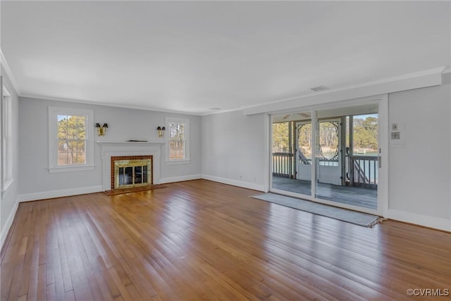 unfurnished living room featuring crown molding, wood finished floors, and a healthy amount of sunlight