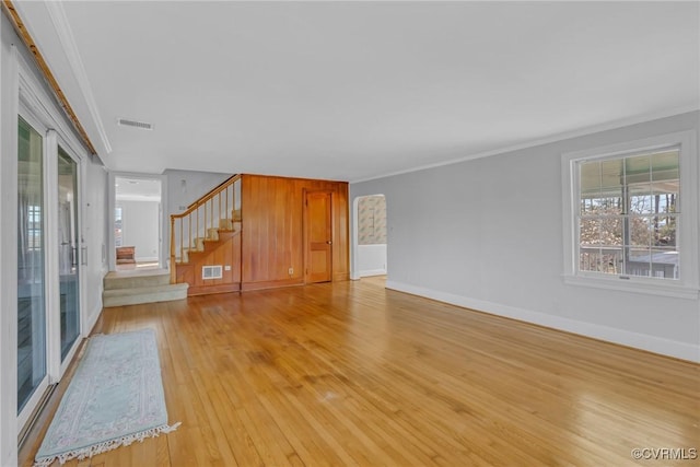 unfurnished living room with visible vents, light wood-style flooring, stairs, and ornamental molding