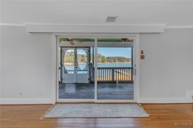 doorway to outside with visible vents, ornamental molding, a ceiling fan, wood finished floors, and baseboards