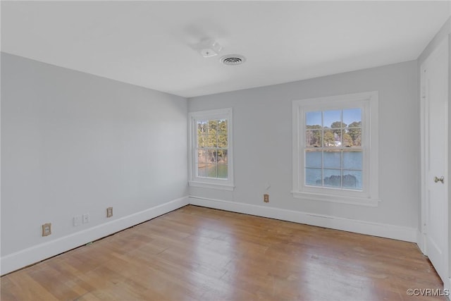 empty room featuring visible vents, baseboards, and wood finished floors