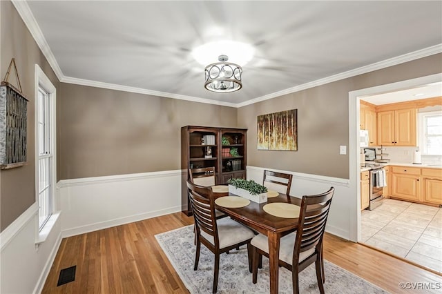 dining room with crown molding, an inviting chandelier, and light hardwood / wood-style flooring