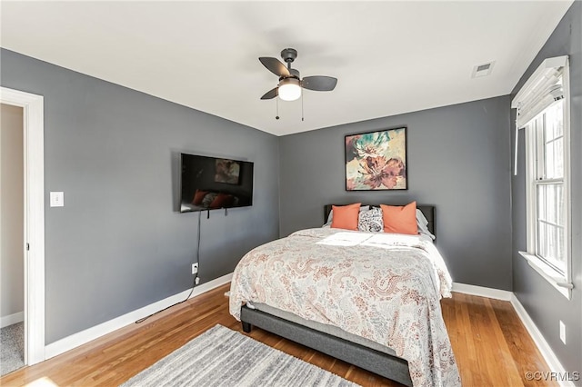 bedroom with ceiling fan, multiple windows, and hardwood / wood-style flooring