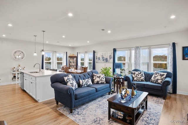 living room with sink, light hardwood / wood-style flooring, and plenty of natural light