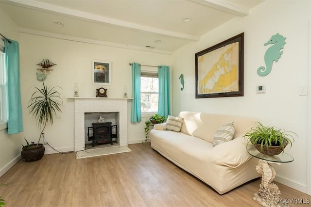 living room featuring beam ceiling, a wood stove, and hardwood / wood-style floors