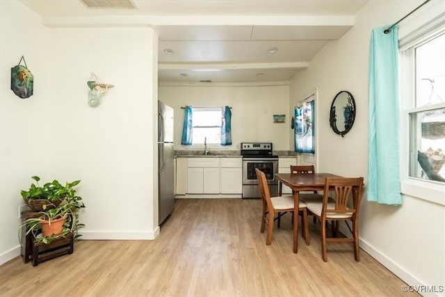 dining room featuring light wood-type flooring, beamed ceiling, and sink