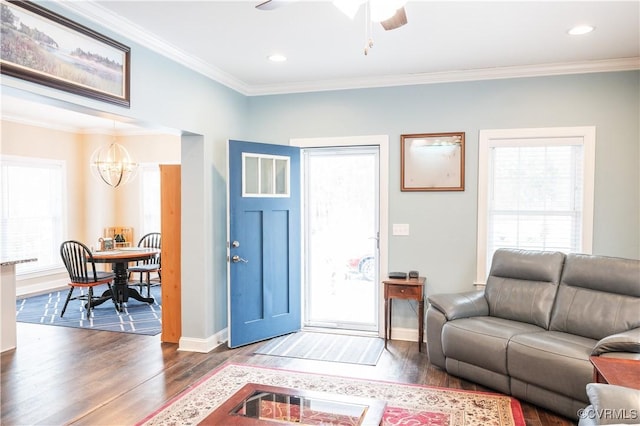 living room with ceiling fan with notable chandelier, dark hardwood / wood-style flooring, and crown molding