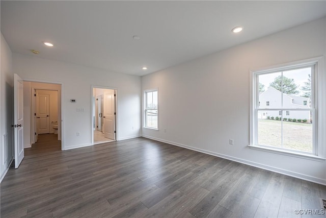 spare room with a wealth of natural light and dark wood-type flooring