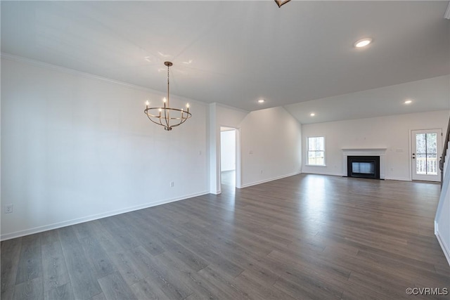 unfurnished living room with dark hardwood / wood-style floors, lofted ceiling, crown molding, and a chandelier