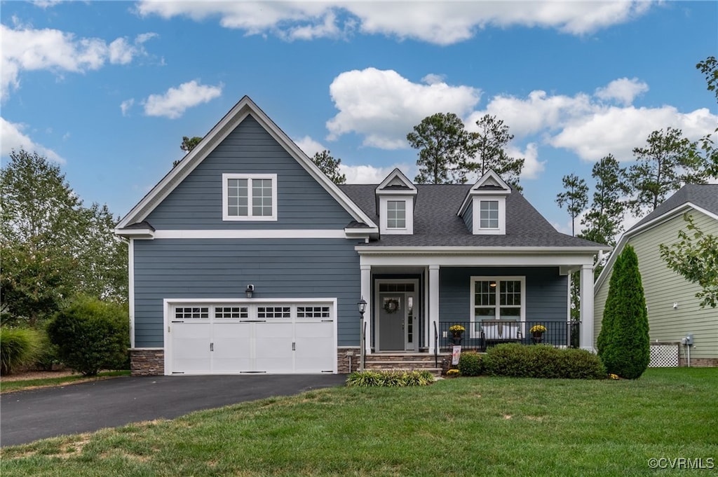 view of front of home featuring covered porch, a garage, and a front lawn