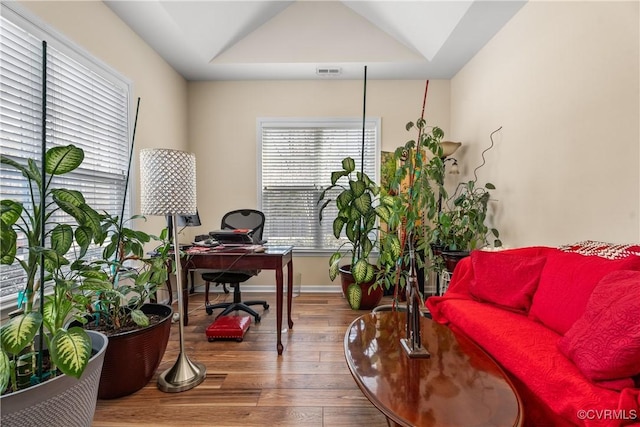 office space featuring hardwood / wood-style flooring and a raised ceiling