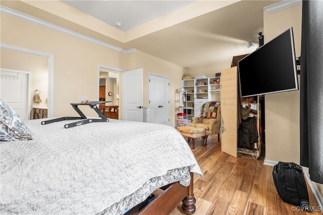 bedroom with hardwood / wood-style flooring, a tray ceiling, and ornamental molding