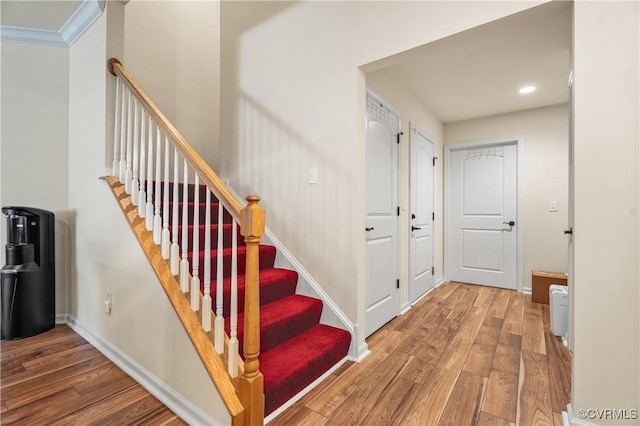 staircase featuring ornamental molding and hardwood / wood-style floors