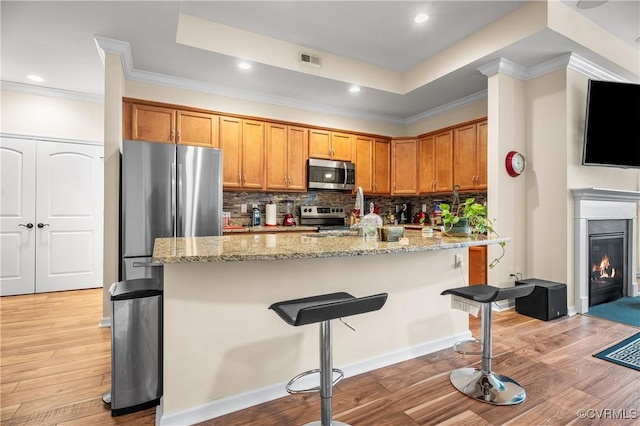 kitchen featuring light stone countertops, a kitchen breakfast bar, crown molding, and stainless steel appliances