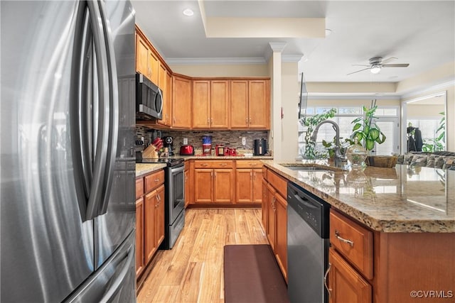 kitchen featuring light stone countertops, stainless steel appliances, light hardwood / wood-style floors, sink, and decorative backsplash