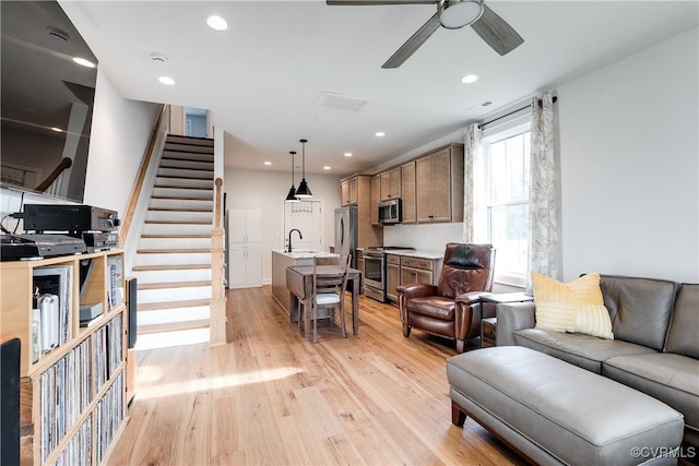 living room featuring light hardwood / wood-style flooring, ceiling fan, and sink