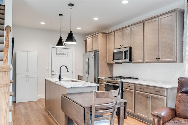 kitchen featuring pendant lighting, sink, light hardwood / wood-style flooring, light stone countertops, and stainless steel appliances