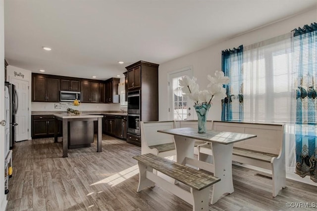 kitchen featuring appliances with stainless steel finishes, a center island, light hardwood / wood-style floors, and dark brown cabinets