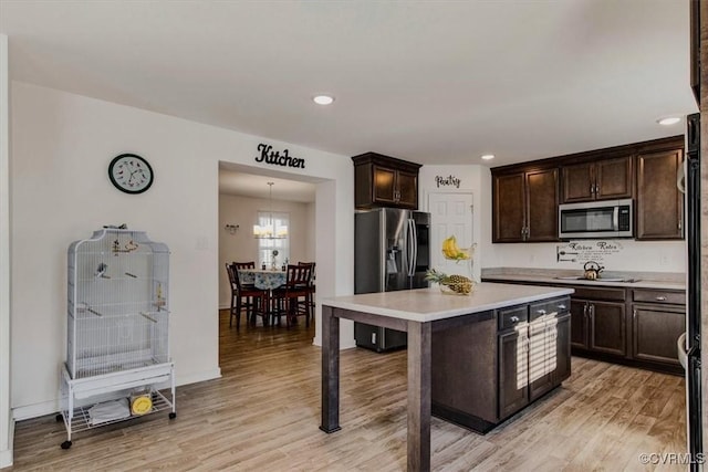 kitchen featuring a center island, a kitchen breakfast bar, light hardwood / wood-style flooring, appliances with stainless steel finishes, and dark brown cabinetry