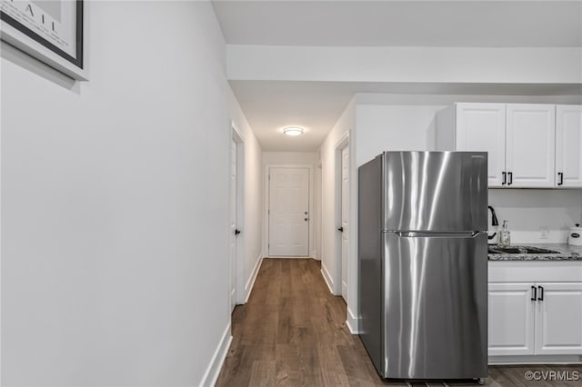 kitchen with sink, light stone counters, dark hardwood / wood-style flooring, white cabinetry, and stainless steel refrigerator